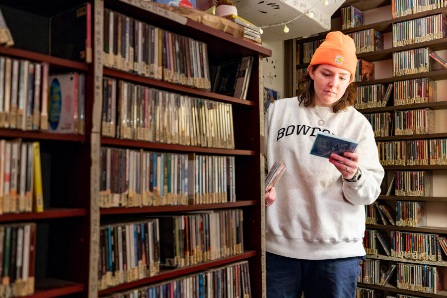 Student surrounded by shelves of CDs, looking at a CD.